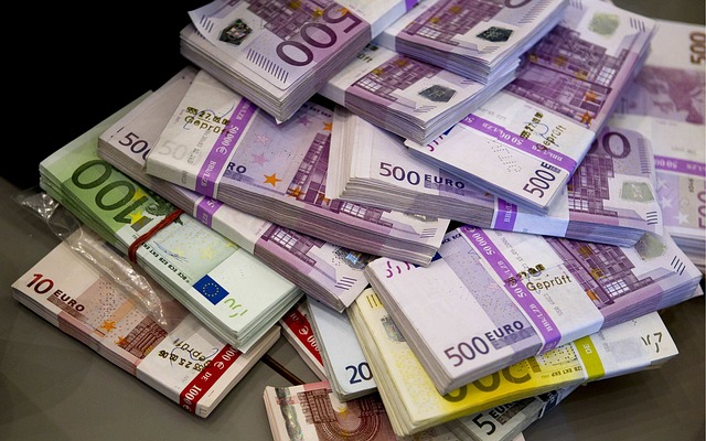 A large number of Euros of varying denominations are splayed on a table 
